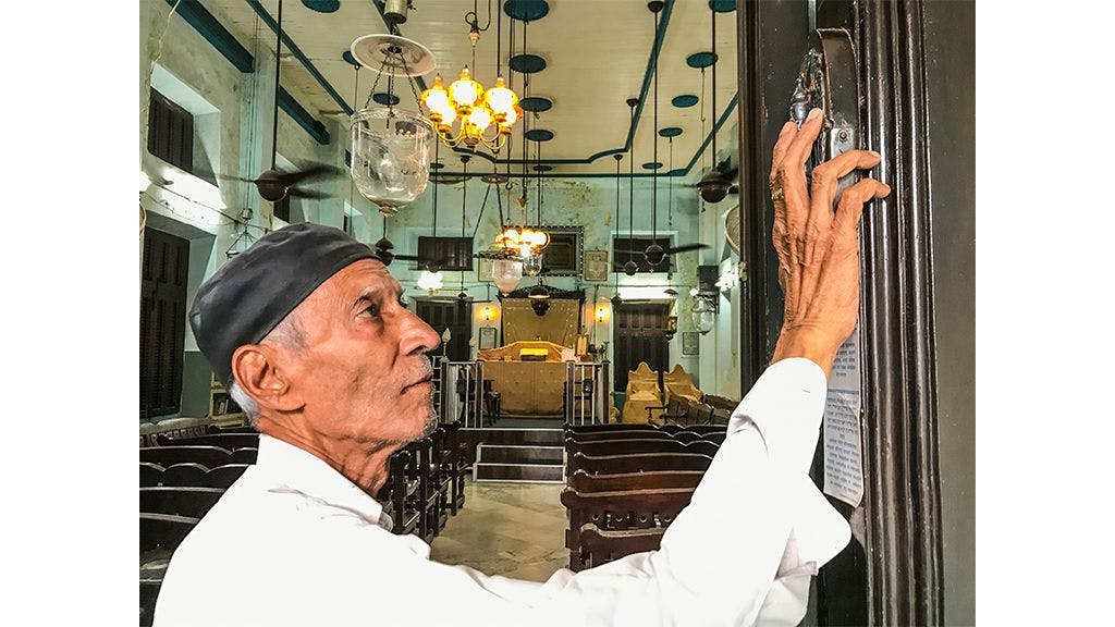 A Bene Israeli man kissing the mezuzah while entering the synagogue