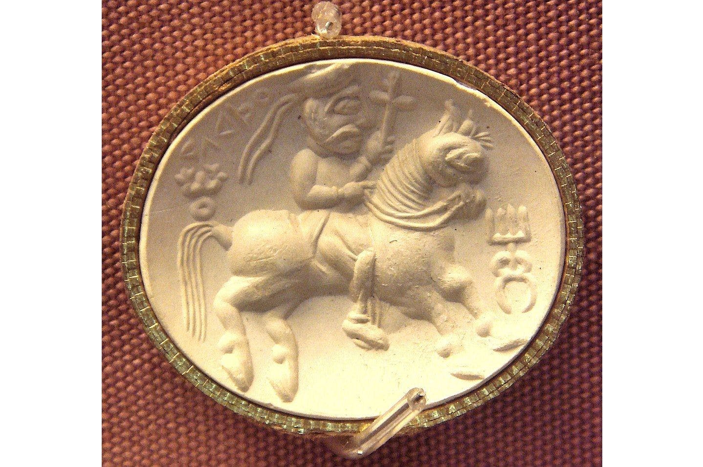 Kushana Carnelian seal representing the Iranian divinity Adsho (ΑΘϷΟ legend in Greek letters), with triratana symbol left, and Kanishka’s dynastic mark right
