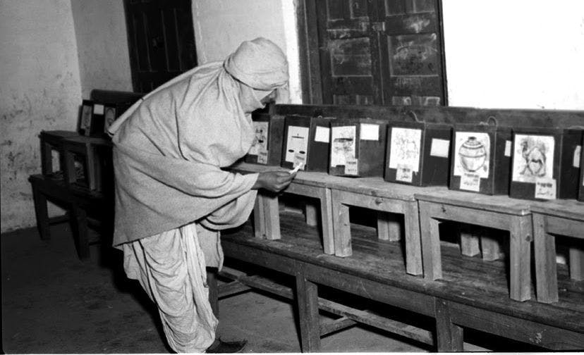 Polling station in Delhi with different ballot boxes, each representing a different party