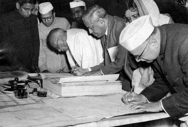 Members of the Constituent Assembly signing the original , handwritten copy of the Constitution of India